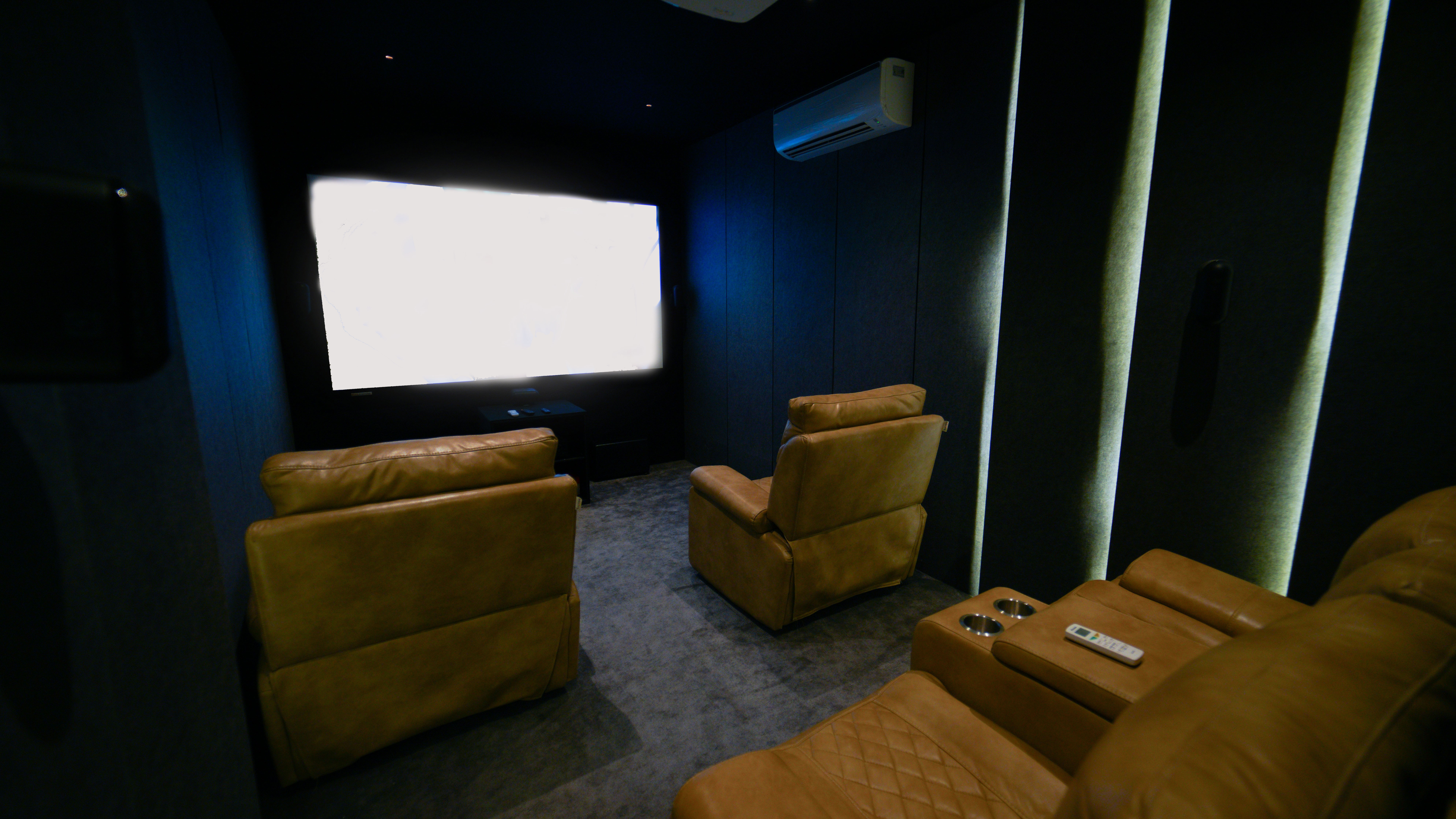 Basement media room remodel with theater seating, sound-dampening walls, custom lighting, and large projection screen.
